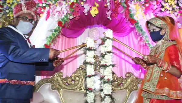 सोशल डिस्‍टेंस वाली शादी: दूल्‍हे-दुल्हन ने एक-दूजे को डंडे से माला पहनाईं, ताकि वायरस का खतरा न हो