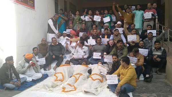 Varanasi News: कफन ओढ़कर जीएसटी कार्यालय के सामने सो गए व्यापारी, अधिकारियों पर लगाए गंभीर आरोप