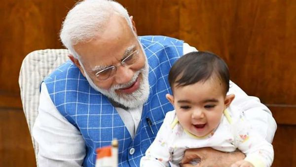 மோடி மடியில் ஒரு குட்டி பாப்பா.. பொக்கை வாய் சிரிப்புடன்... அடடே யாருப்பா அது!