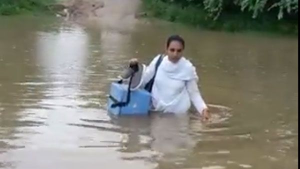 మహిళా ఏఎన్ఎం సాహసం: కోవిడ్ వ్యాక్సిన్ పంపిణీ కోసం నడుంలోతు నీటిలో..(వీడియో)