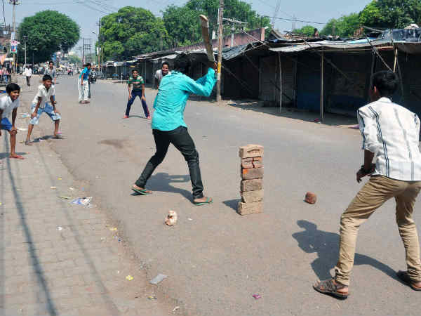 सड़क पर क्रिकेट का मज़ा लेते युवा 