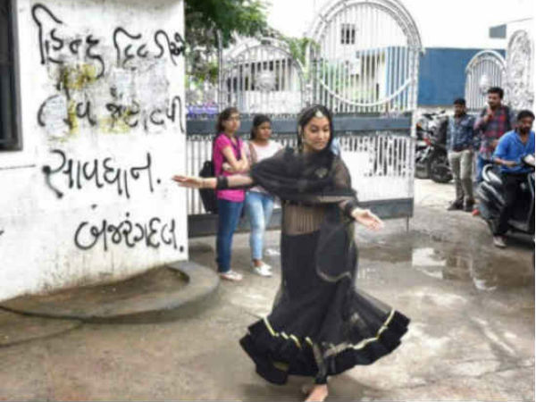 दीवार पर लिखी गए स्लोगन के सामने नृत्य 