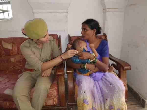 woman police constable feeding baby with milk on her lap