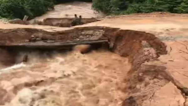 Terrifying moment motorcyclist and passenger plunge into flash flood after bridge collapses in Cambodia.
