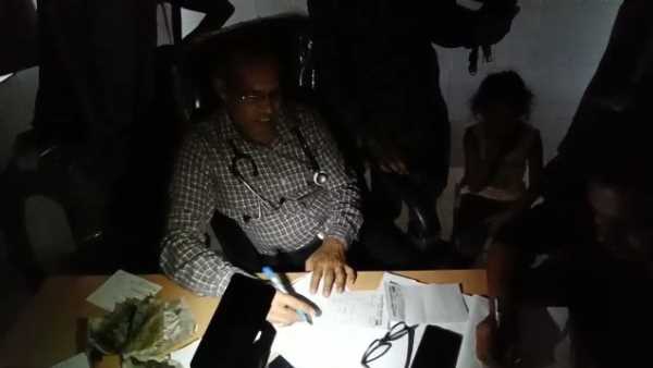 doctors treating patient with mobile torch light in hospital