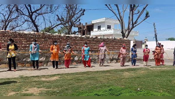 एक-दूजे से एक-एक मीटर की दूरी पर खड़ी हुईं महिलाएं