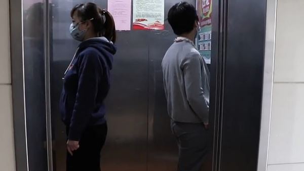 लिफ्ट में दो से तीन लोग, दीवार की तरफ मुंह