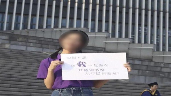 साइन बोर्ड लेकर खड़ी लड़की