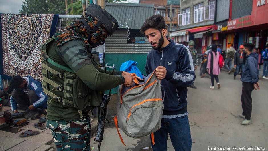 श्रीनगर में बाजार में लोगों के सामान टटोलता एक सुरक्षाकर्मी