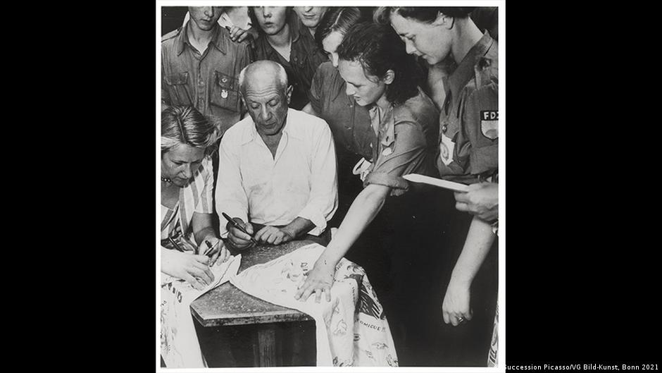 फ्री जर्मन युथ युवा संगठन के सदस्यों के लिए डिजाइन किए हुए कपड़ों पर हस्ताक्षर करते पिकासो फ्री जर्मन युथ युवा संगठन के सदस्यों के लिए डिजाइन किए हुए कपड़ों पर हस्ताक्षर करते पिकासो