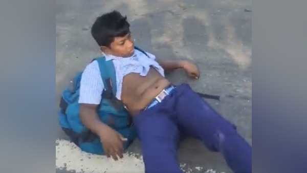 स्कूल ड्रेस पहने एक लड़का बस से सड़क पर गिरा