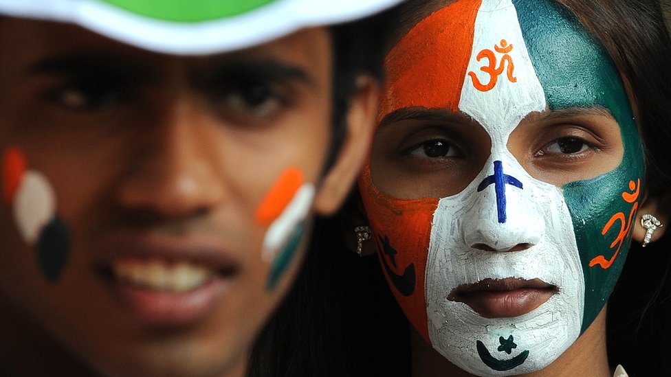 चेहरे पर चारों धर्म के प्रतीकों को पेंट किए हुए युवती