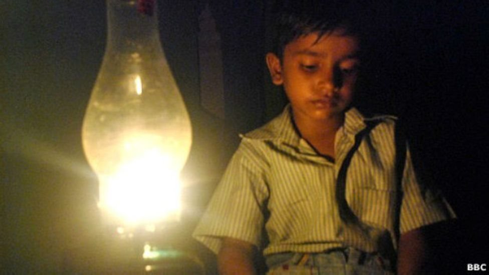 बल्ब की रोशनी में बैठा बच्चा