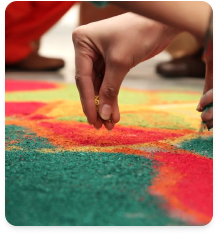 A hand sprinkling coloured powder to make a rangoli