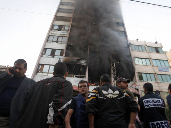 People in front of a damaged building in gaza city
