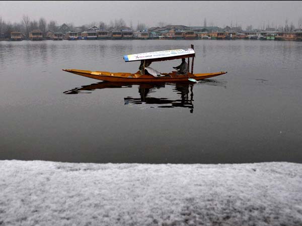 A boatman rowing his boat along Dal Lake