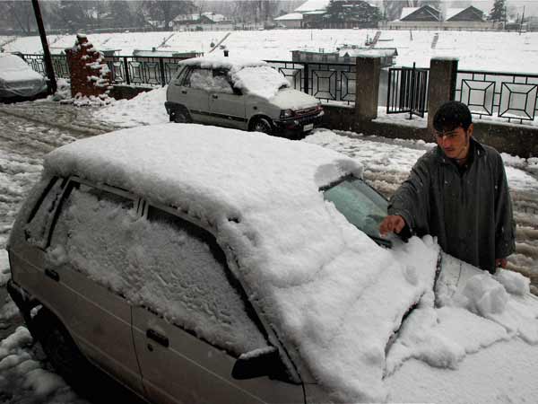 A man cleans snow from his car 