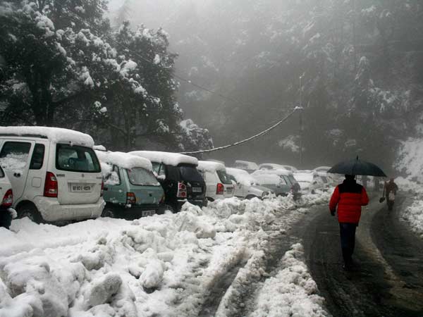 A man walks with an umbrella at Lakkar Bazar