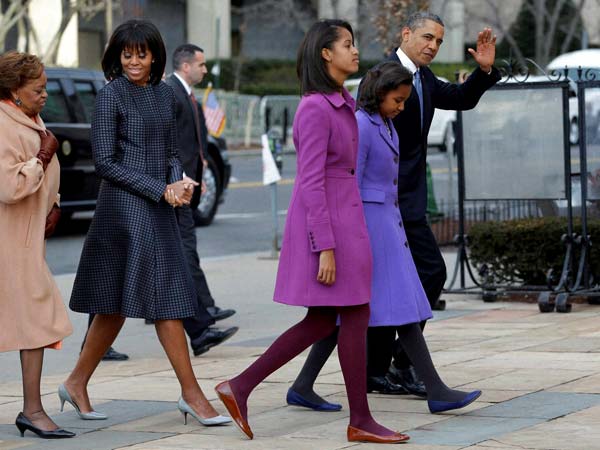 Barack Obama waves as he walks with his daughters