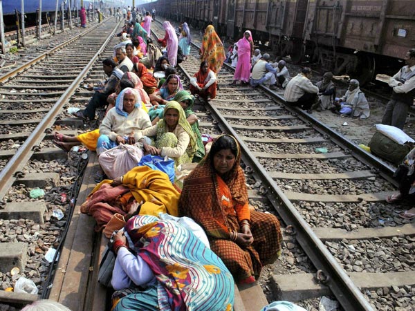 Passengers sit on railway tracks