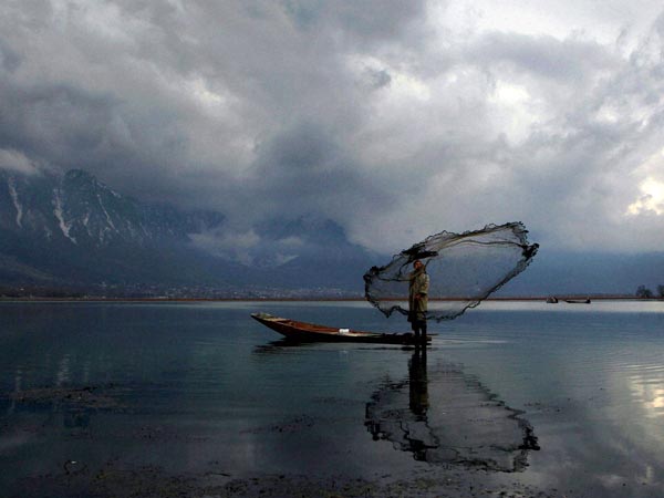 A fisherman casts his net at the Dal Lake A fisherman casts his net at the Dal Lake