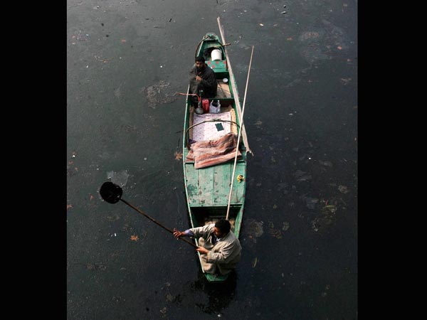 A Boatman breaking the frozen waters of Dal Lake A Boatman breaking the frozen waters of Dal Lake
