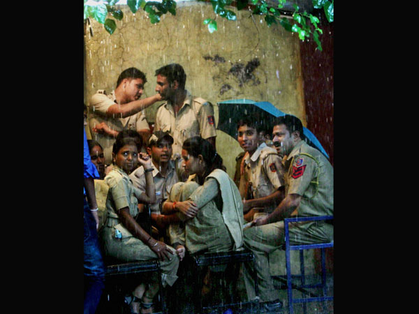 Police personnel take shelter during heavy rain