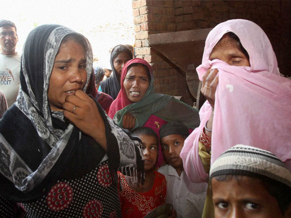 Riot victims crying at a makeshift camp 