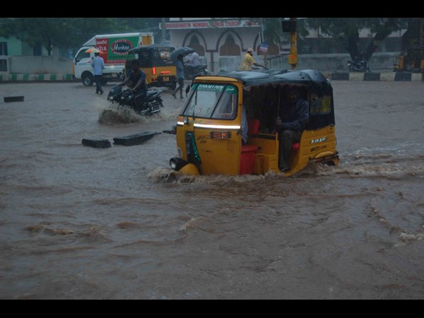 An autorickshaw wades through an water-logged street