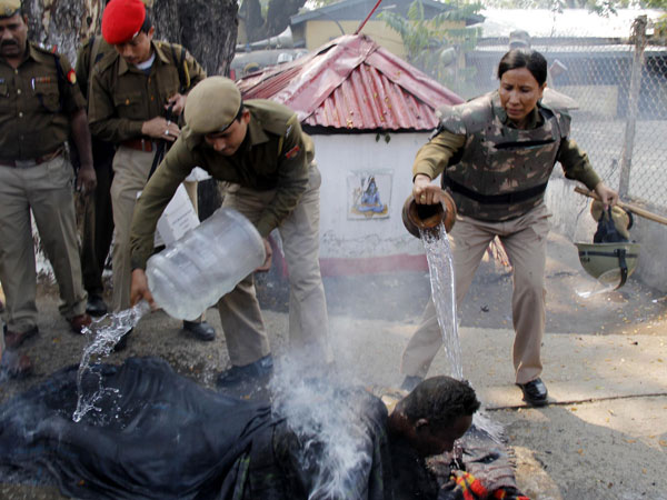 Police personnel pour water on a KMSS activist