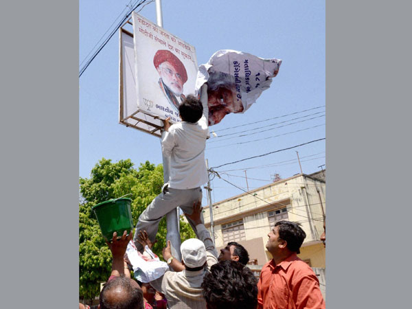 Madhunsudan Mistry pasting his poster over a poster of Narendra Modi