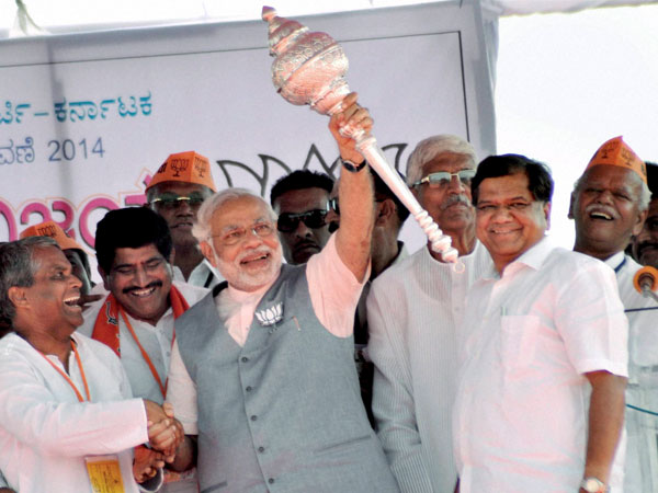 Narendra Modi holds a mace at an election rally at Bagalkot