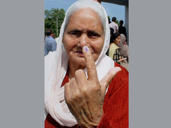 An elderly woman shows her inked finger