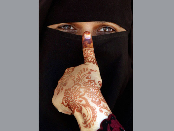 A burqa-clad woman shows her inked thumb