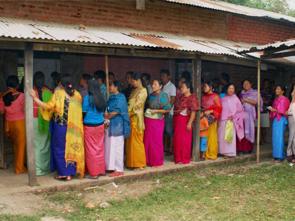 Women wait in queue to cast their votes for Lok Sabha elections