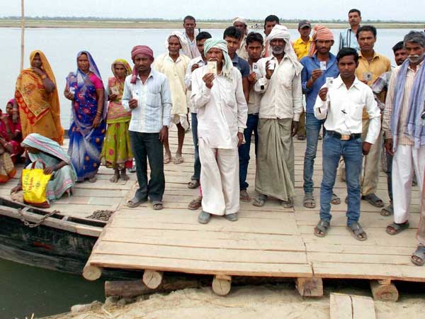 Voters show their Voter ID cards as they arrive by a boat
