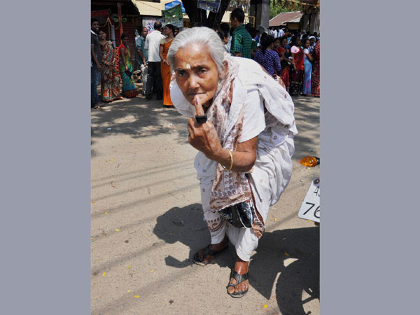 An old woman shows her inked finger after casting her vote