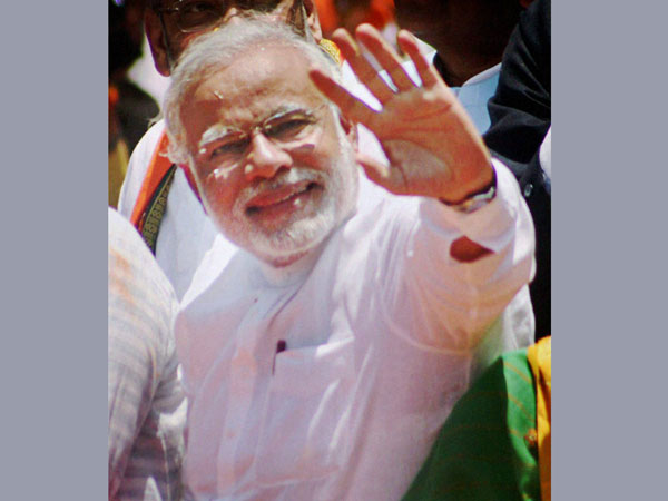 Narendra Modi waves at supporters during a road show