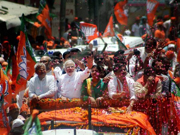 Narendra Modi waves at supporters during a road show