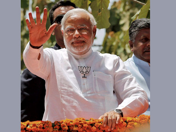 Narendra Modi waves at supporters during a road show