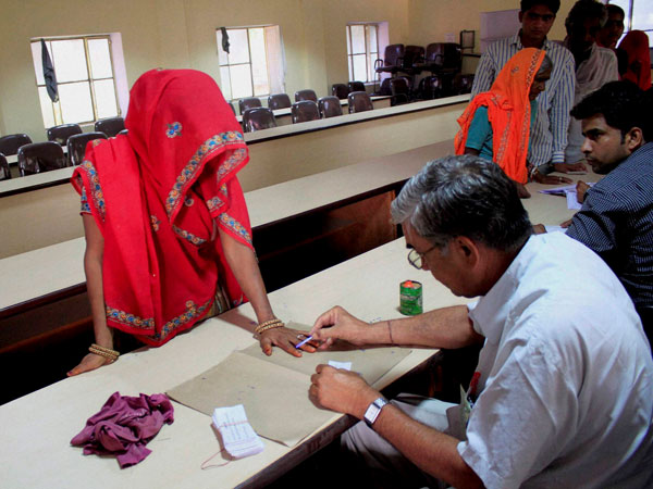 A polling officer inks the finger of a woman voter