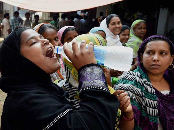 A Muslim women quenches her thirst at a polling station