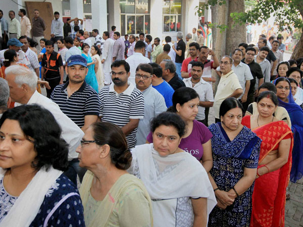 People wait in queues to cast their votes
