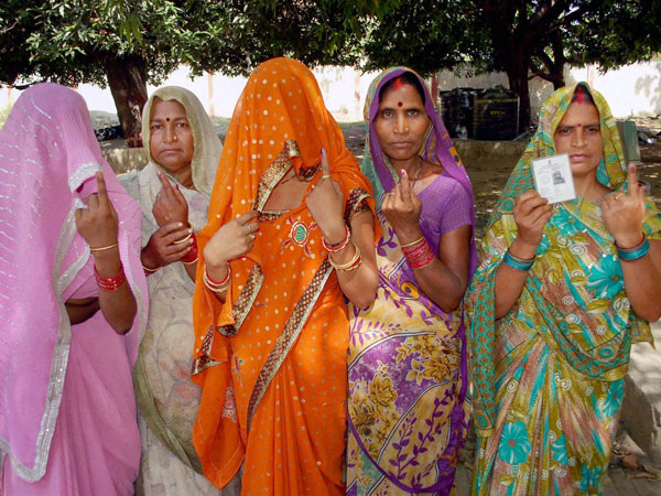 Village women show their inked fingers after casting votes