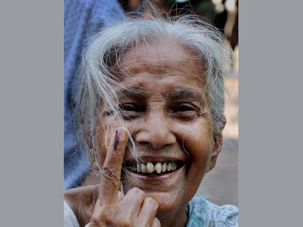 An elderly woman voter showing her ink-marked finger