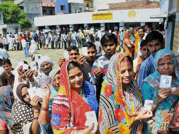 People wait in queues at a polling station to cast their votes