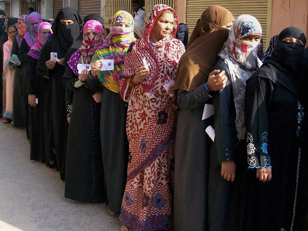 Muslim voters wait in a queue to cast their votes