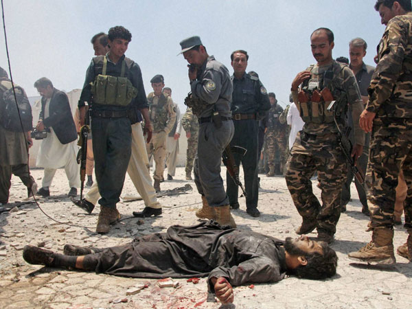 Afghan security forces gather around the lifeless body