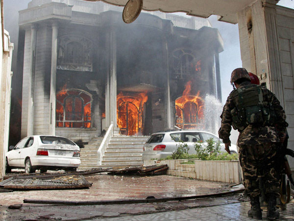 Afghan security forces watch a house burn at the site 