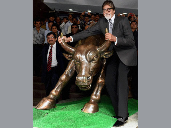 Bollywood actor Amitabh Bachchan poses with the bull statue